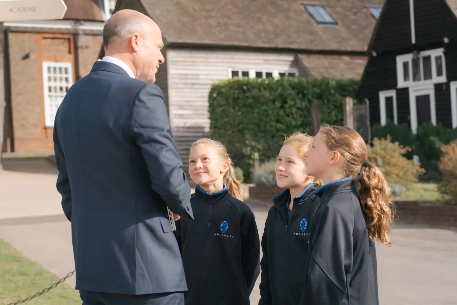The head talking to a group of pupils outside the main school building Image of the head talking to a group of pupils outside the main school building