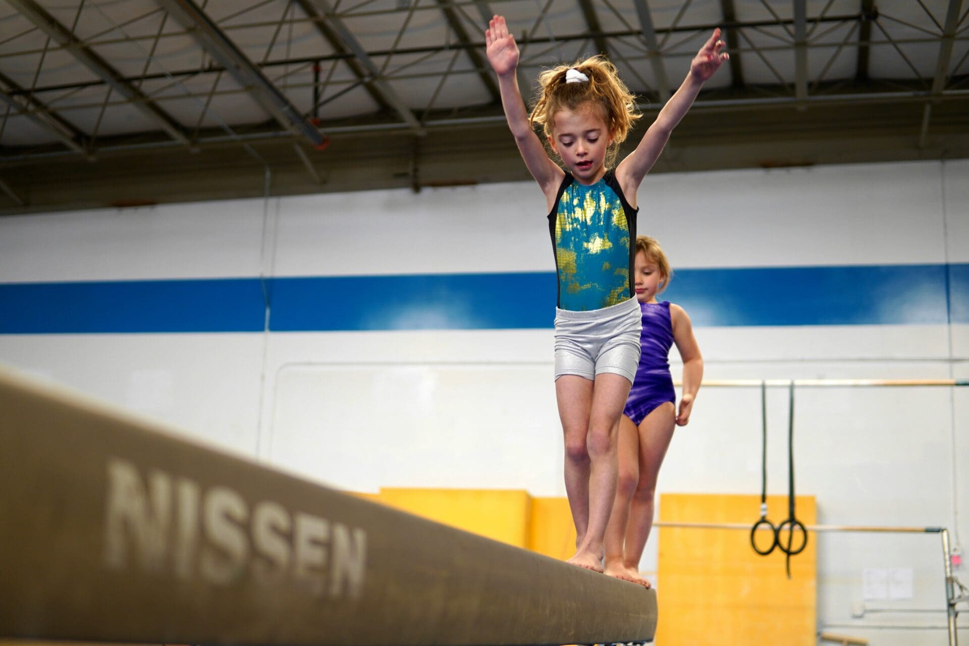 Image of a young pupil walking on a balance beam in gymnastics club